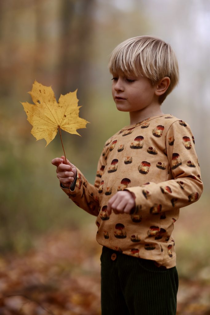 Junge in handgefertigter Kinderkleidung mit Pilzen